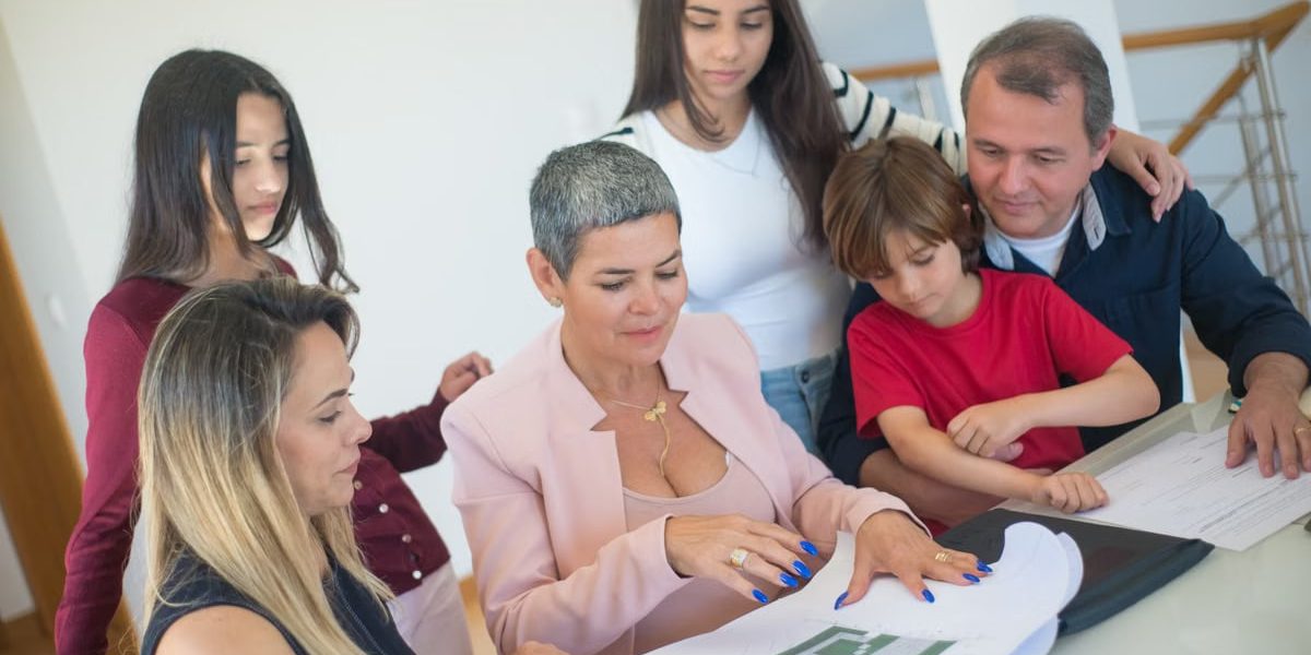 A family discusses property plans with a realtor indoors, focused on purchasing a new home.