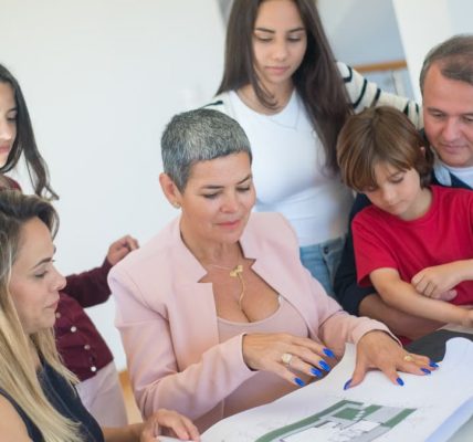 A family discusses property plans with a realtor indoors, focused on purchasing a new home.